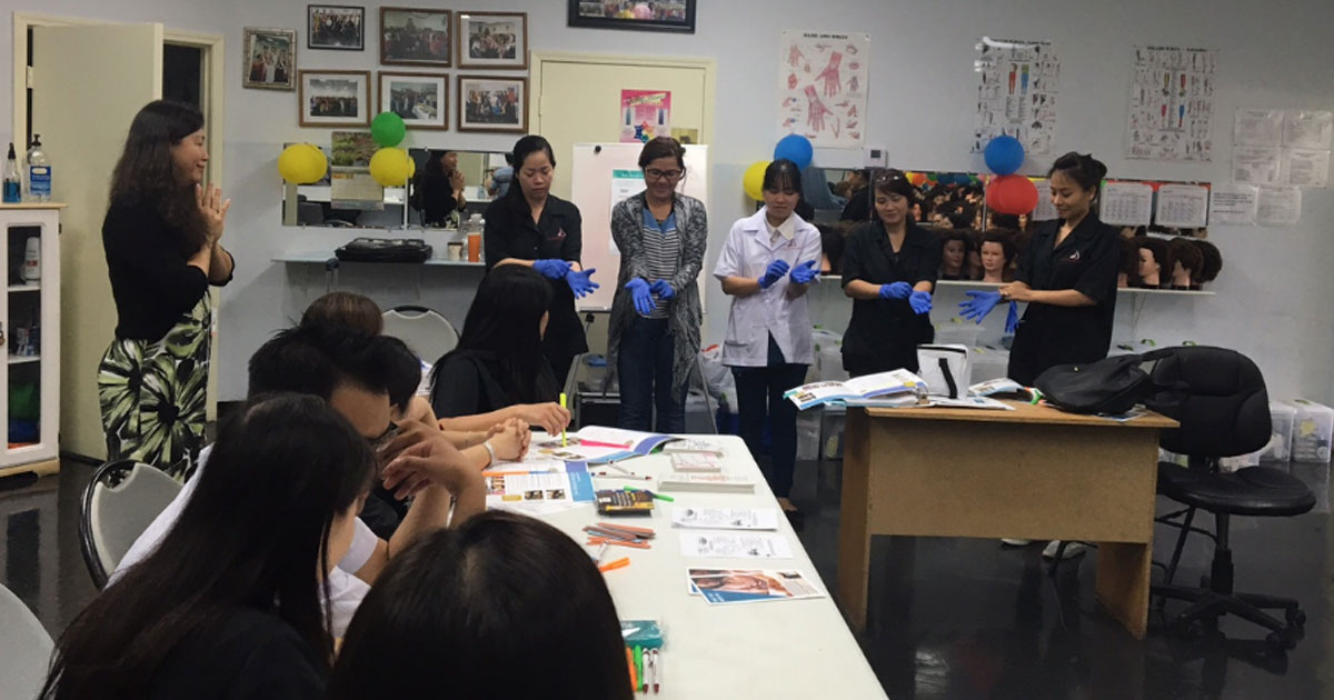 Yen Giai Ly (left) observes as nail salon workers practice correctly removing gloves