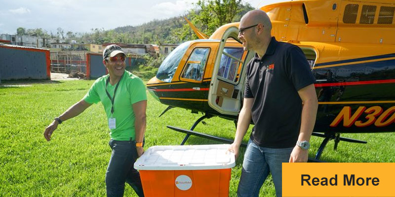 Two people carrying medical supplies from helicopter