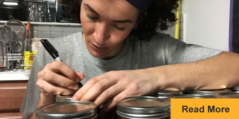 person writing messages on mason jars