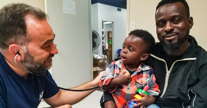 Dr. Laszlo Madaras provides a check-up to a child held by their parent