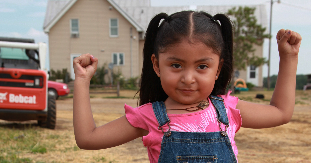 A girl flexes her arms to show strength