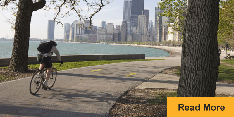 Bicyclist riding on path in daytime with citycape