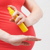 pregnant woman applying insect repellent to arm