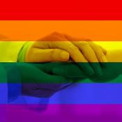 physician holding patients hand with pride flag behind