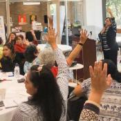 Women raise their hands as part of a presentation at the Women's Conference