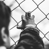 Child holding on to wire fence