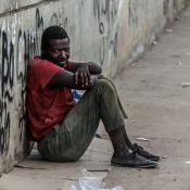 homeless man sitting on sidewalk