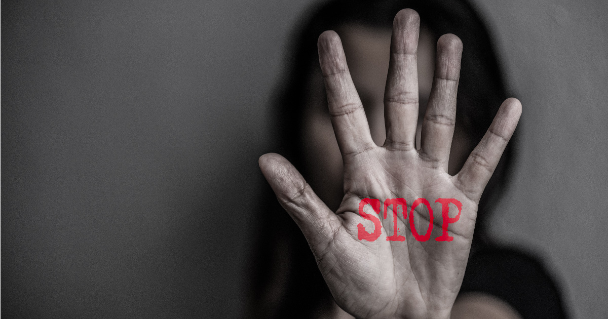 Woman holding up hand with the word 'STOP' written on it