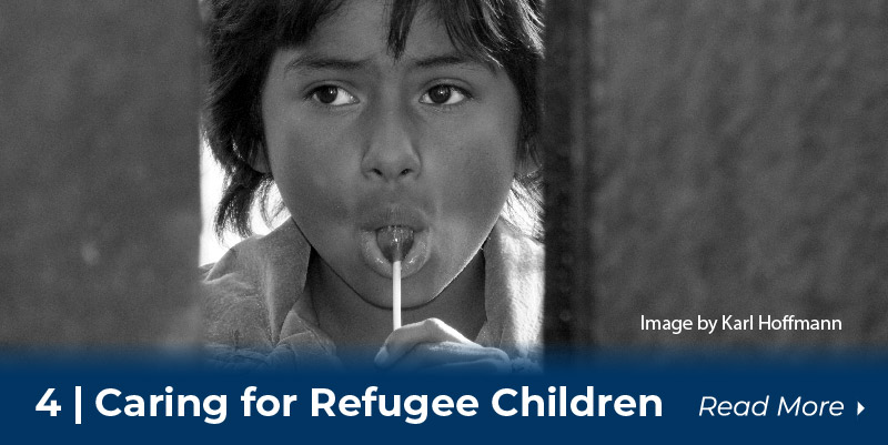 Child with candy looks through gap in fence