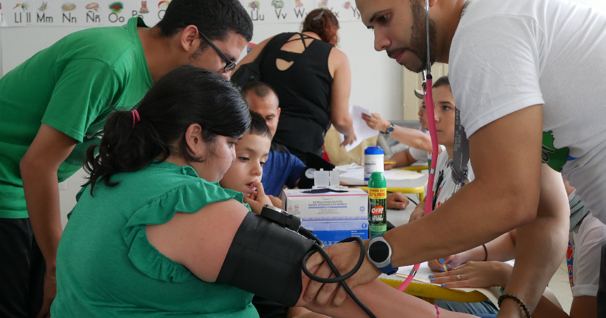 A healthcare worker in Puerto Rico sees to a family after a hurricane