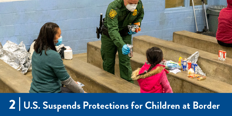 A border patrol officer hands food to a child in a detention facility