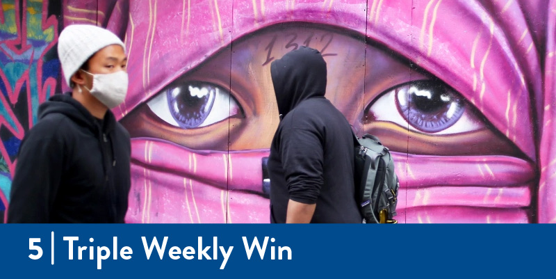 People walk past a newly painted mural