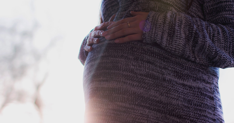 A pregnant woman next to a sunrise