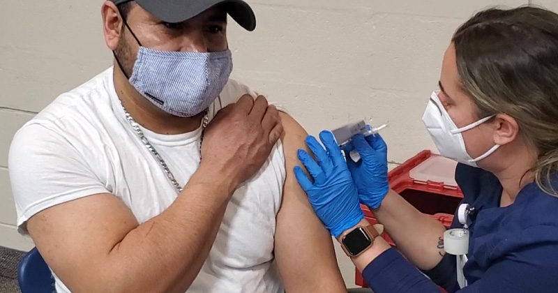 A man receives a vaccination from a clinician