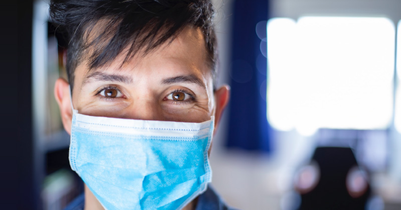 A person in a mask looks toward camera