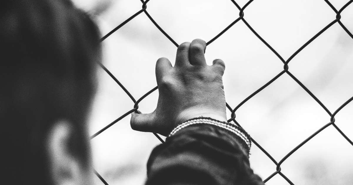 Child with hand on fence