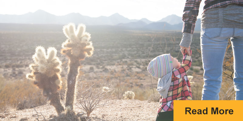 woman and child holding hands in desert